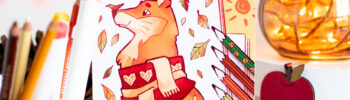 Le livre « Petits Coloriages d'Automne », dont la couverture représente un renard portant une écharpe, est exposé au milieu d'un décor sur le thème de l'automne, de feutres de couleur et d'un bocal rempli de guirlandes lumineuses orange.