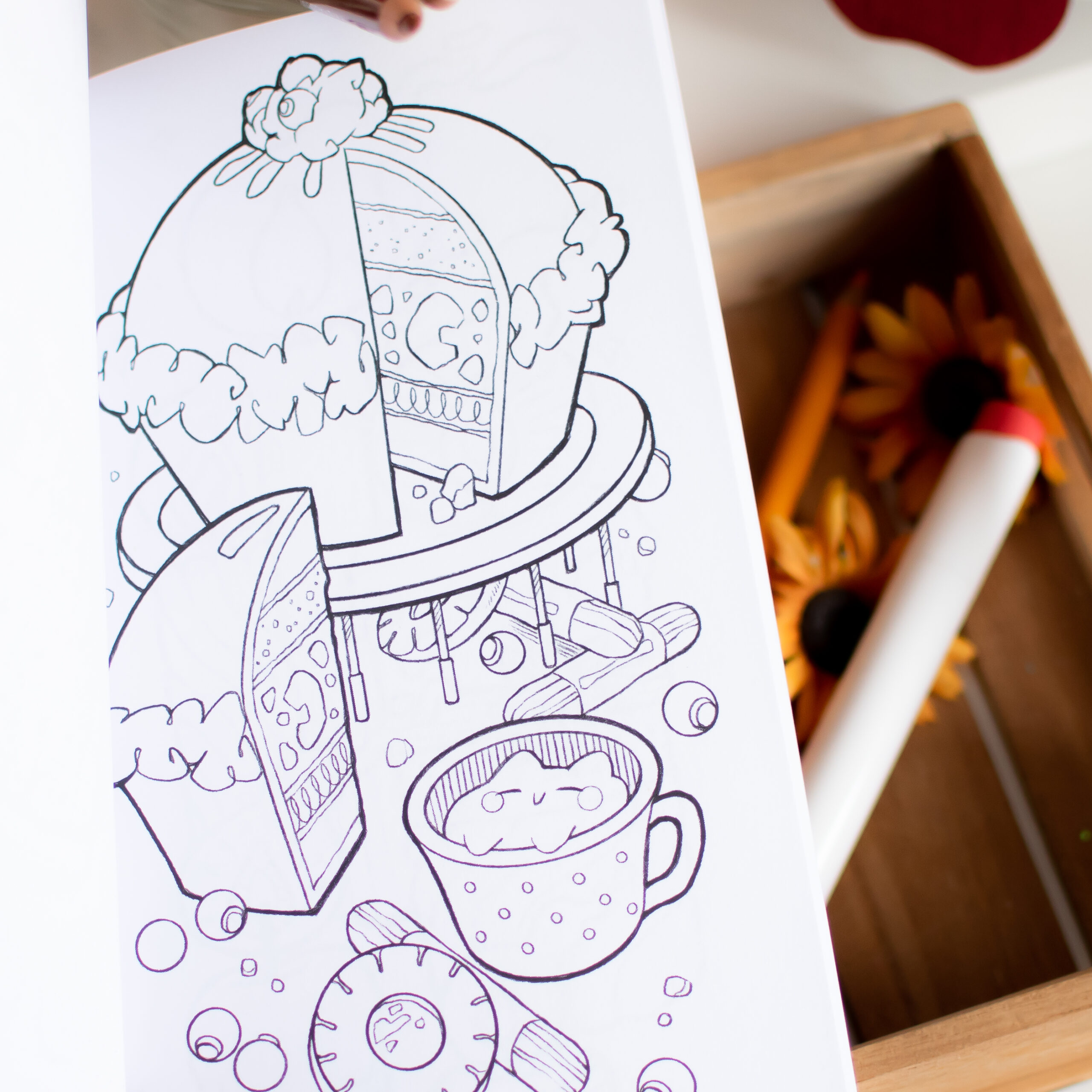 « Petits Coloriages d'Automne » propose une page de coloriage en noir et blanc représentant un grand gâteau (dont une part a été découpée), un gobelet, des bonbons et une horloge, le tout prêt à être colorié. Une boîte de matériel de dessin se trouve à proximité.