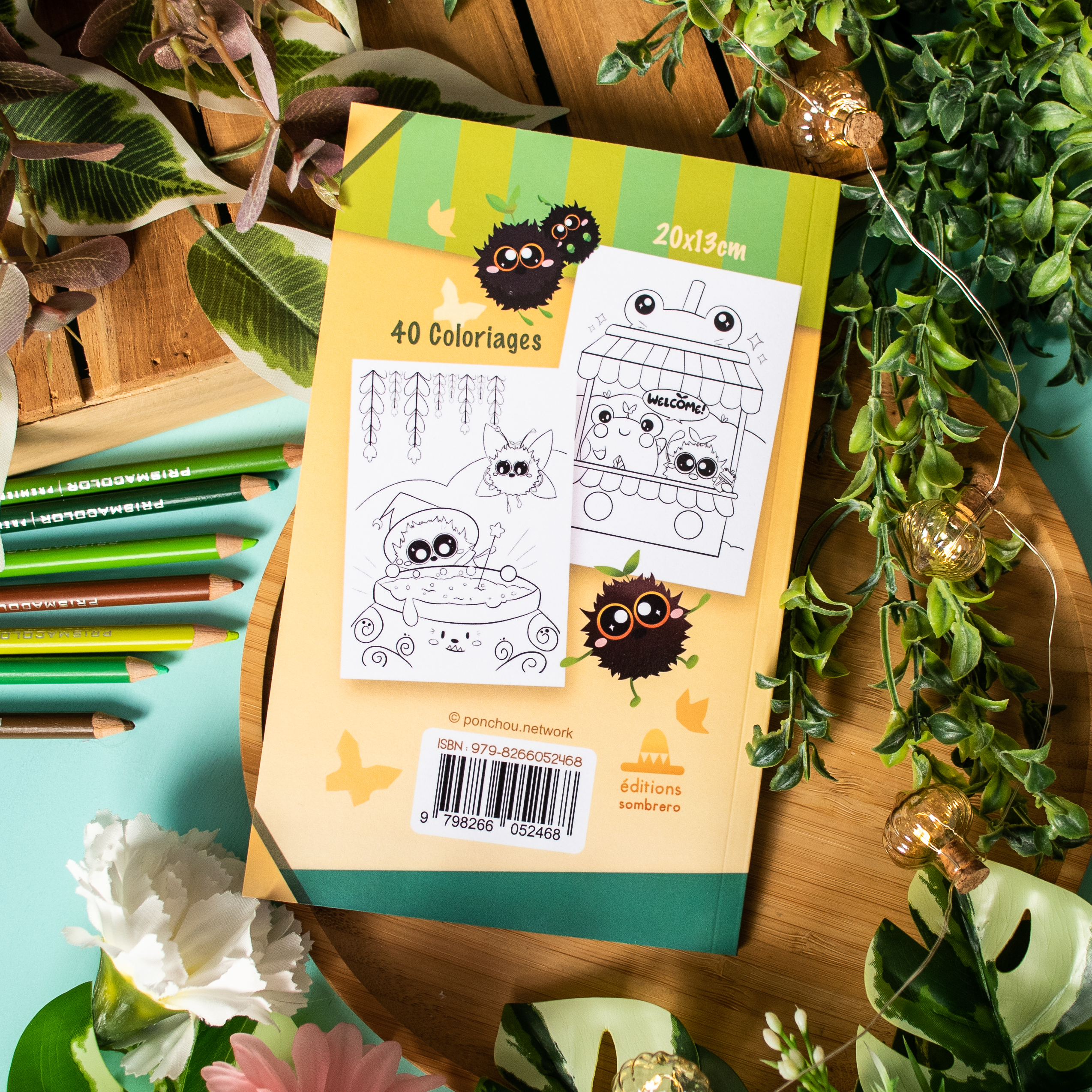 Le livre « Coloriages de Poussiérons », qui met en scène d'adorables personnages de dessins animés et propose 40 coloriages au dos de la couverture, repose sur une surface en bois, entouré de crayons verts, de feuilles, de fleurs et de deux pages de coloriage fantaisistes sur le thème des animaux.