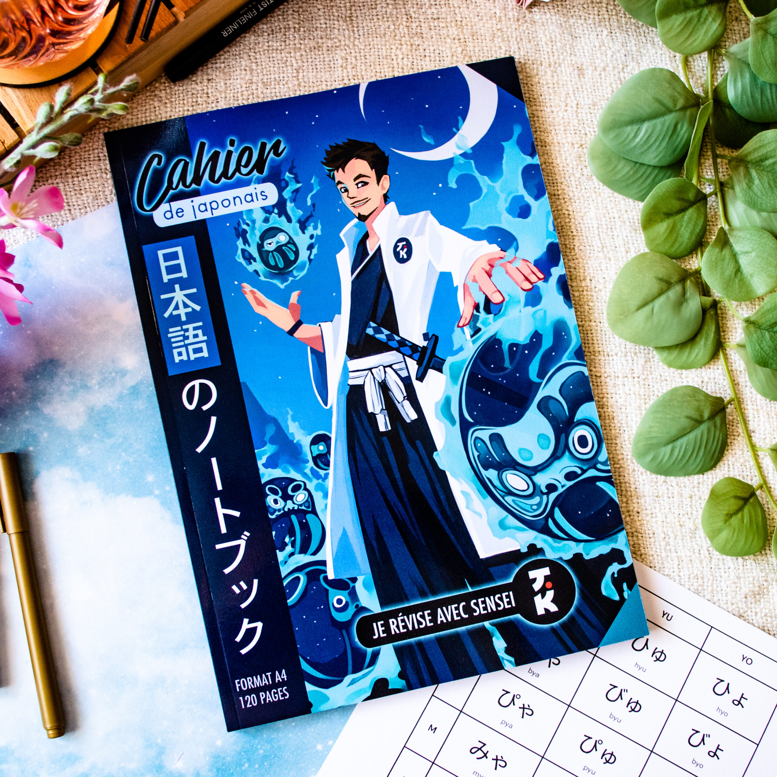 Voici une version remaniée de votre phrase en utilisant les informations fournies sur le produit : Le « Cahier de japonais : Je révise avec Sophie 先生 Sensei » est un cahier au format A4 dont la couverture colorée représente un personnage de style anime entouré d’esprits bleus lumineux. Posé sur un bureau orné de feuilles vertes, avec un stylo et une fiche d'exercices de hiragana à proximité, ce cahier de japonais de 120 pages est idéal pour étudier.