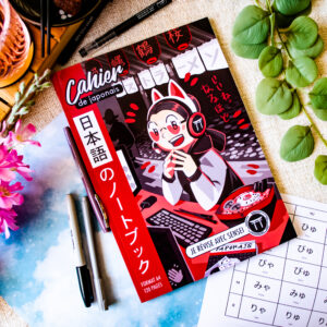 Le « Cahier de japonais : Je révise avec Sophie Sensei » (format A4, 120 pages), un cahier de japonais orné d'une couverture aux couleurs vives dans le style manga, est présenté au milieu d'un décor composé de fleurs, de feuilles vertes, de stylos et d'une fiche d'entraînement aux hiragana, le tout sur un fond à motifs floraux.