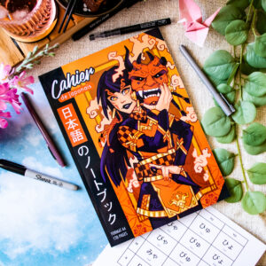 Le « Cahier de Japonais : Je révise avec Sophie 先生 Sensei » (format A4, 120 pages), dont la couverture est illustrée d’une femme vêtue d’une armure de samouraï, est posé sur un bureau aux côtés de stylos, d’une plante, d’une tasse de thé et d’une fiche d’exercices sur les hiragana.