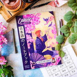 Le « Cahier de Japonais : Je révise avec Sophie 先生 Sensei » (120 pages), au format A4, dont la couverture illustrée représente une femme en kimono assise sous des cerisiers en fleurs, est posé sur une table à motifs, entouré de fleurs, d'articles de papeterie, d'un en-cas et d'une fiche d'exercices de japonais.