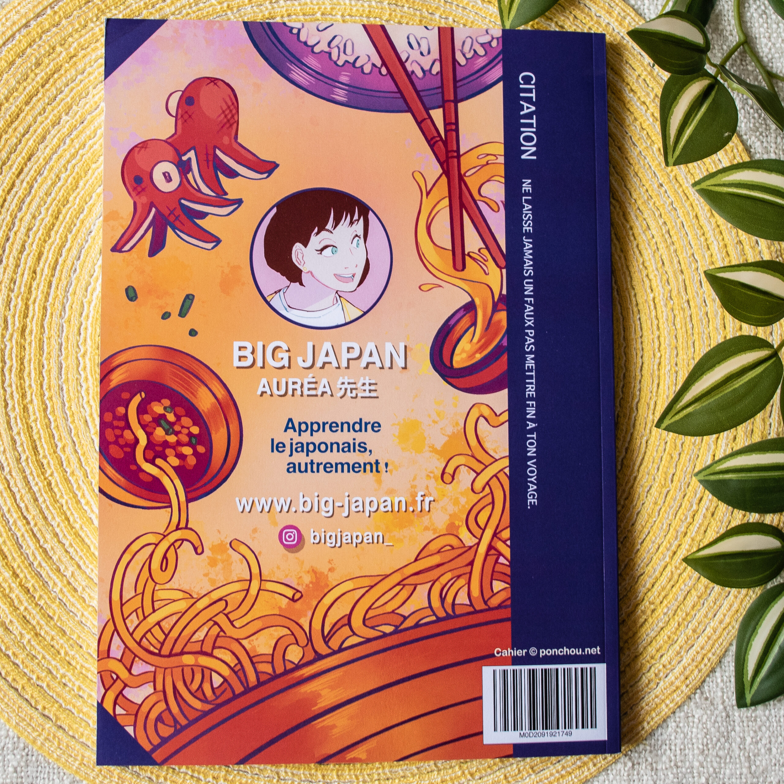 La quatrième de couverture d'un cahier d'exercices coloré en japonais, sur laquelle figurent des nouilles, des sushis, un poulpe et le dessin d'une personne souriante aux cheveux courts. On y voit du texte en français et en japonais, ainsi qu'un lien vers un site web.